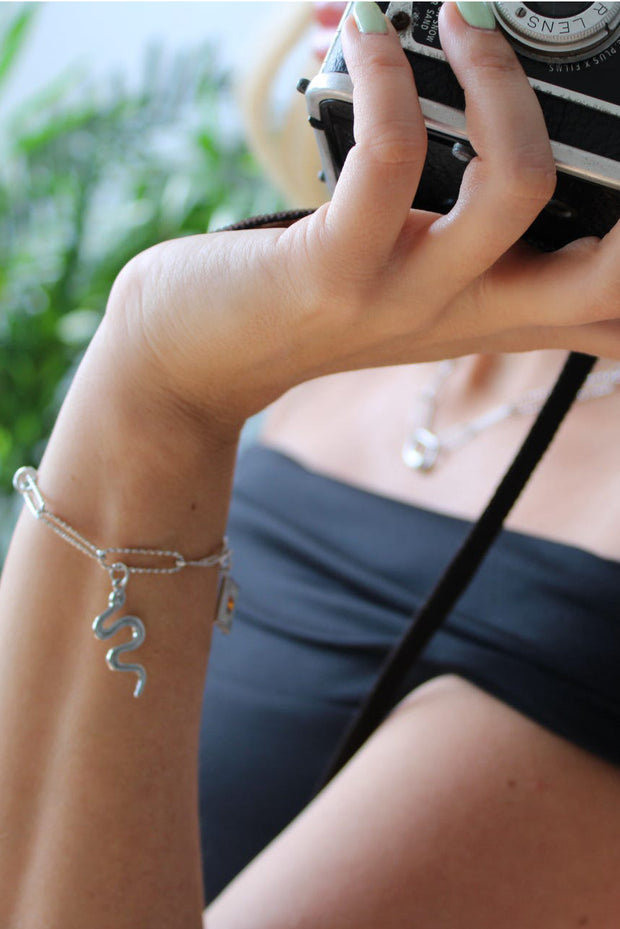 Woman carrying camera wearing silver charm bracelet.