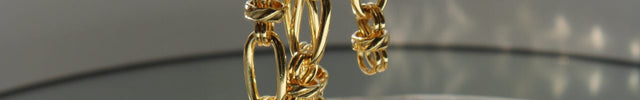 A fork lifting gold chains from a glass plate. 
